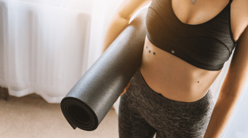 woman holding black yoga mat featured