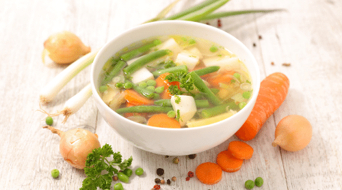 bowl of vegetable soup with ingredients around it featured