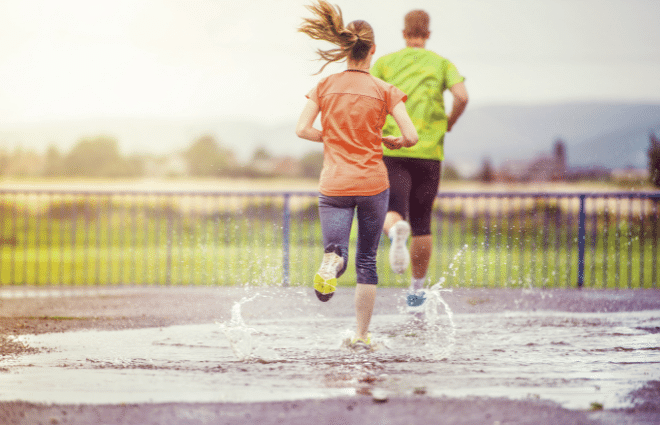 Man and woman running in the rain and big puddle