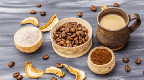 Mug of mushroom coffee, small dishes with coffee beans, coffee grounds, and powdered mushrooms on table with coffee beans and dried mushroom pieces around