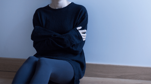 Woman with anxiety sitting on floor with arms crossed