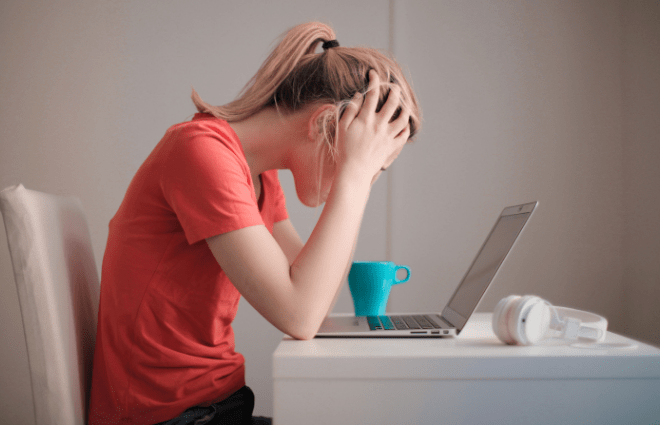 Stressed woman sitting at desk with laptop and coffee